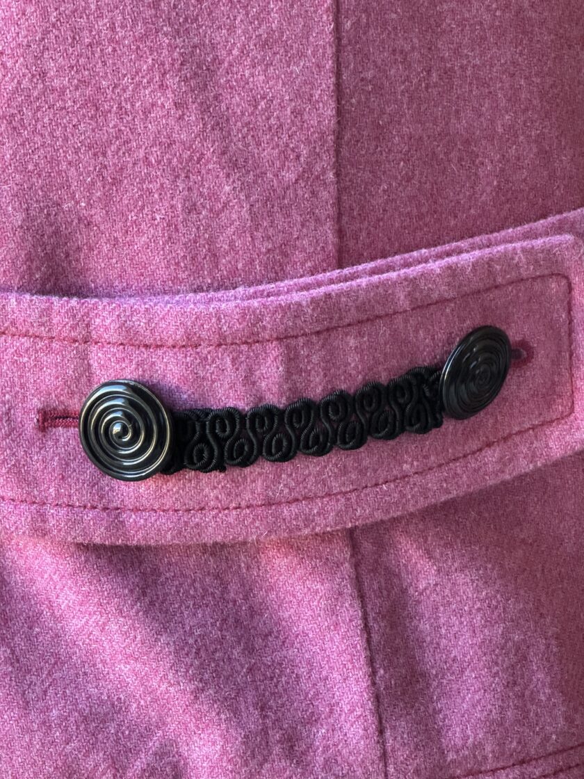 A close up of a pink jacket with black buttons.