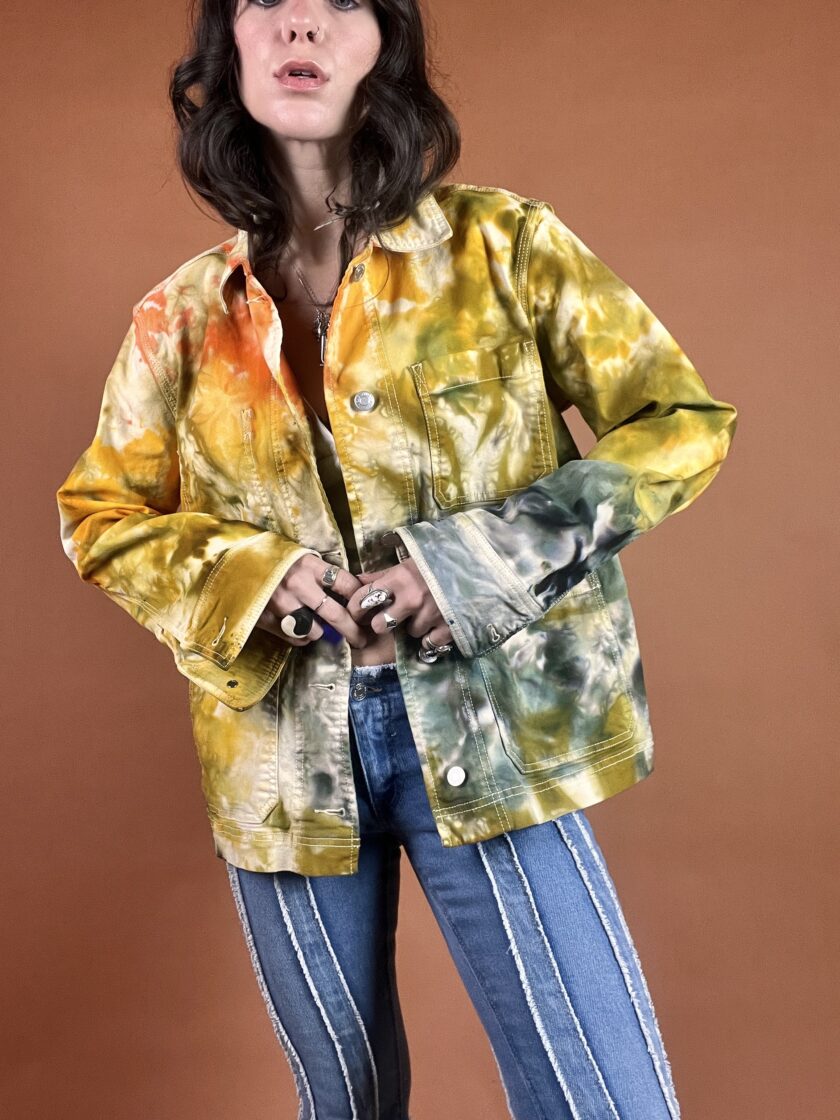A woman wearing a tie dye jacket and jeans.