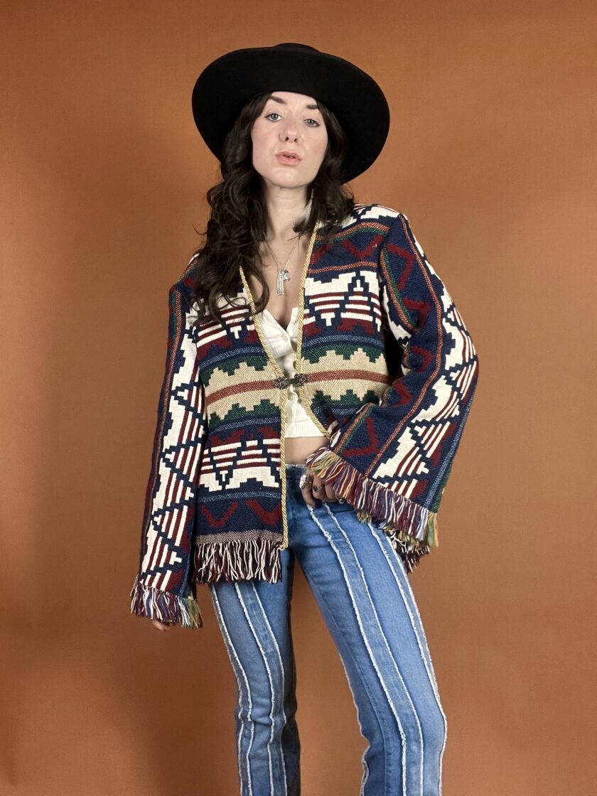 A woman in a hat and jeans is posing for a photo.