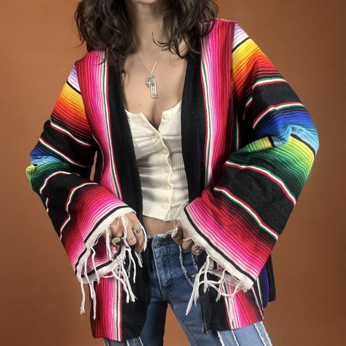 A woman wearing a colorful mexican jacket.