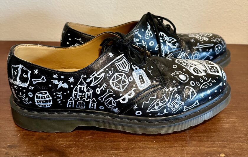 A pair of black shoes with white drawings on them.