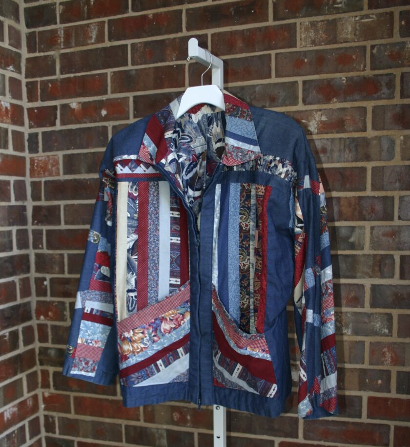 A blue and red jacket hanging on a brick wall.