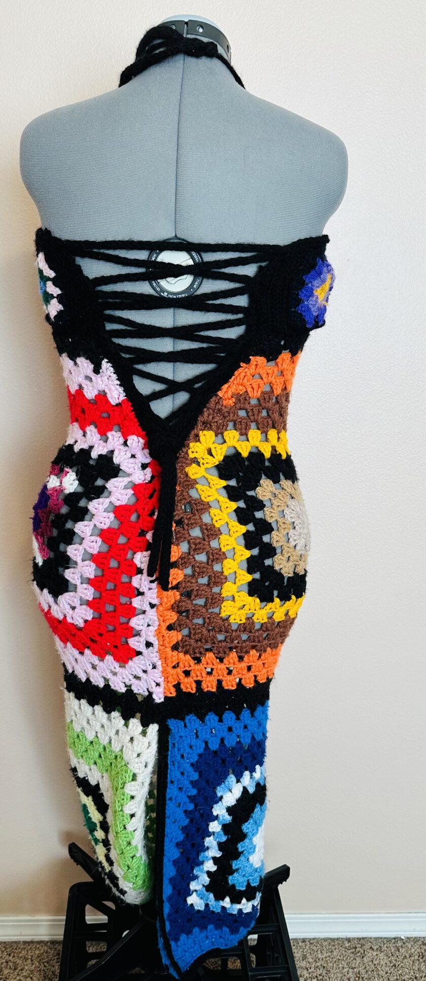 A colorful crocheted dress on a mannequin.