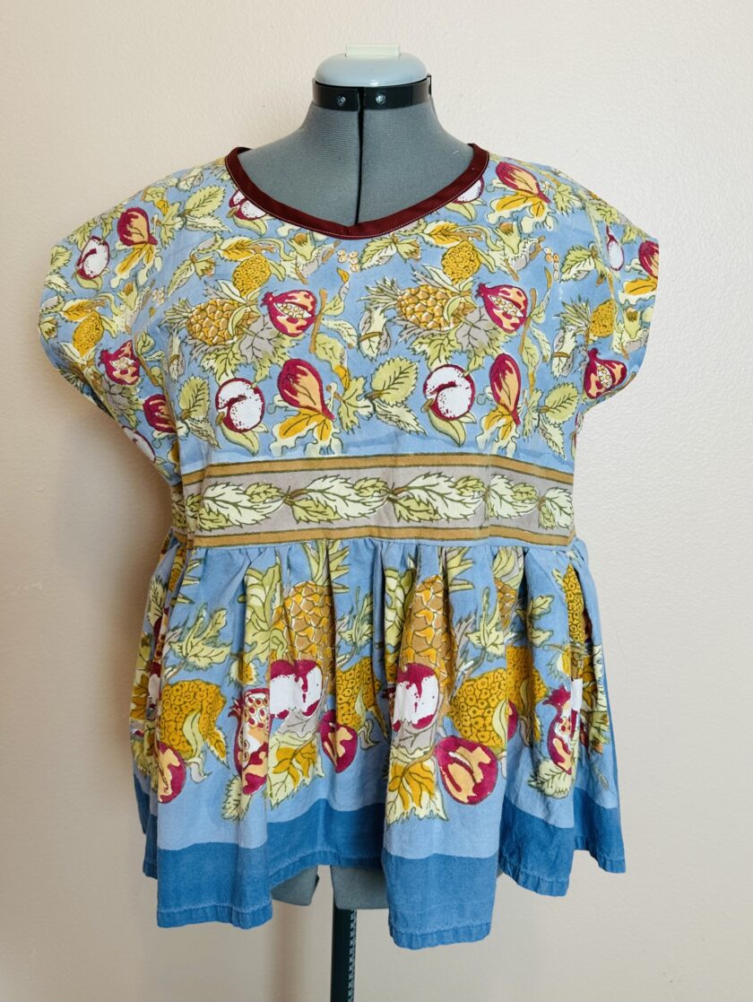 A blue and yellow peasant blouse on a mannequin dummy.