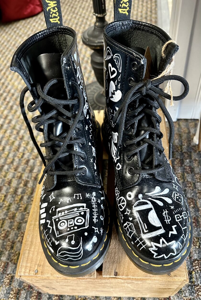 A pair of black boots with white drawings on them.