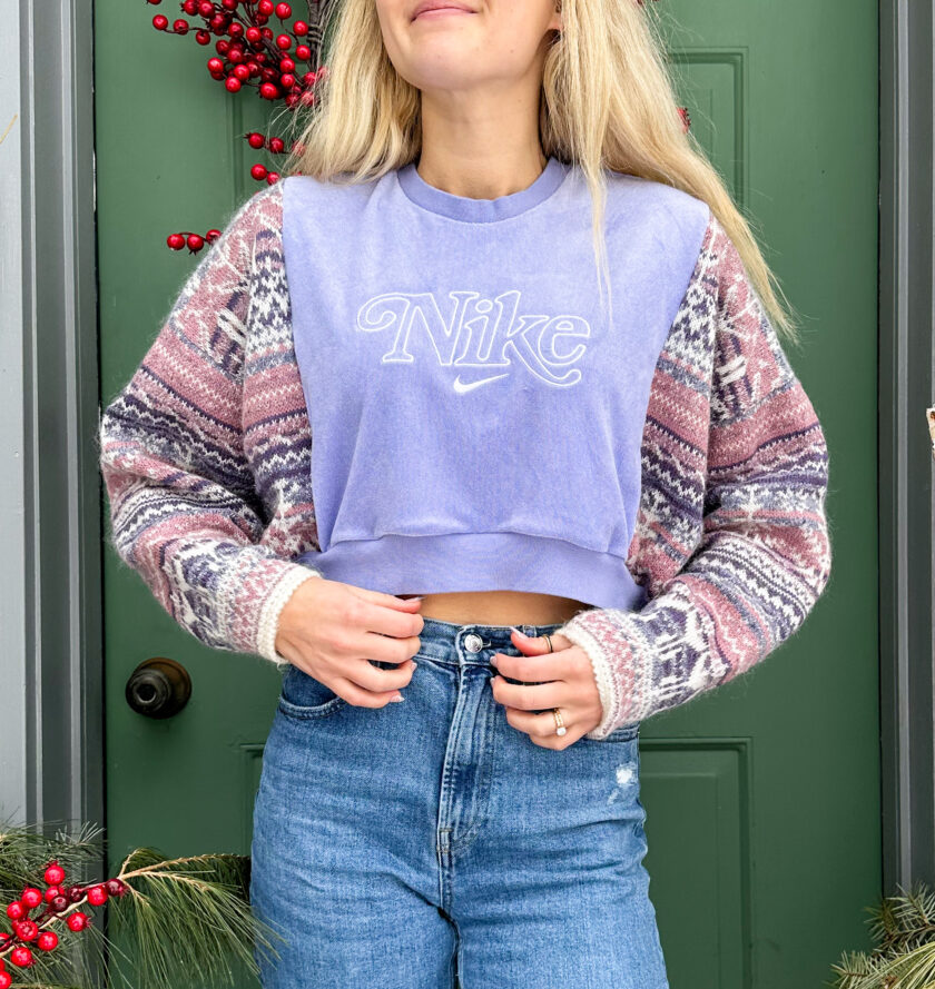 A woman wearing a purple nike cropped sweater standing in front of a christmas tree.