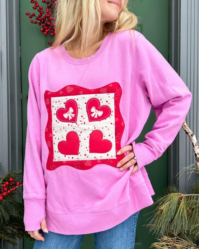 A woman wearing a pink sweatshirt with hearts on it.