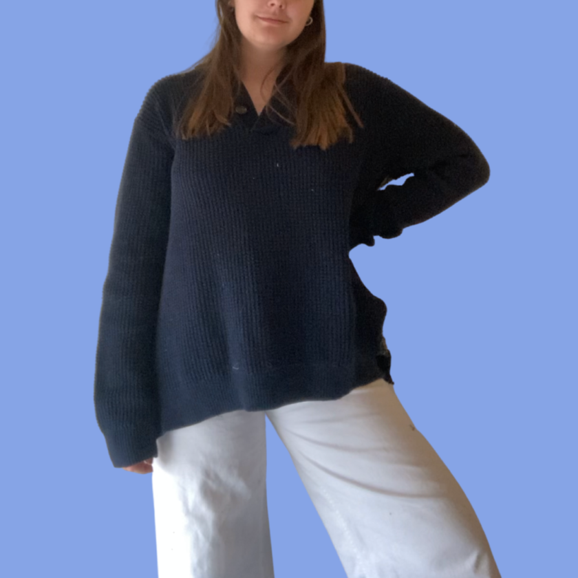 A woman wearing a black sweater and white pants.