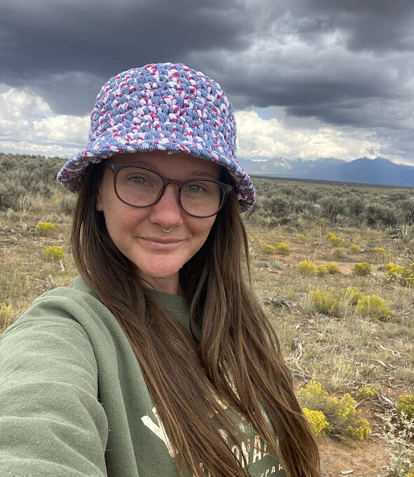 A woman wearing glasses and a hat in the desert.