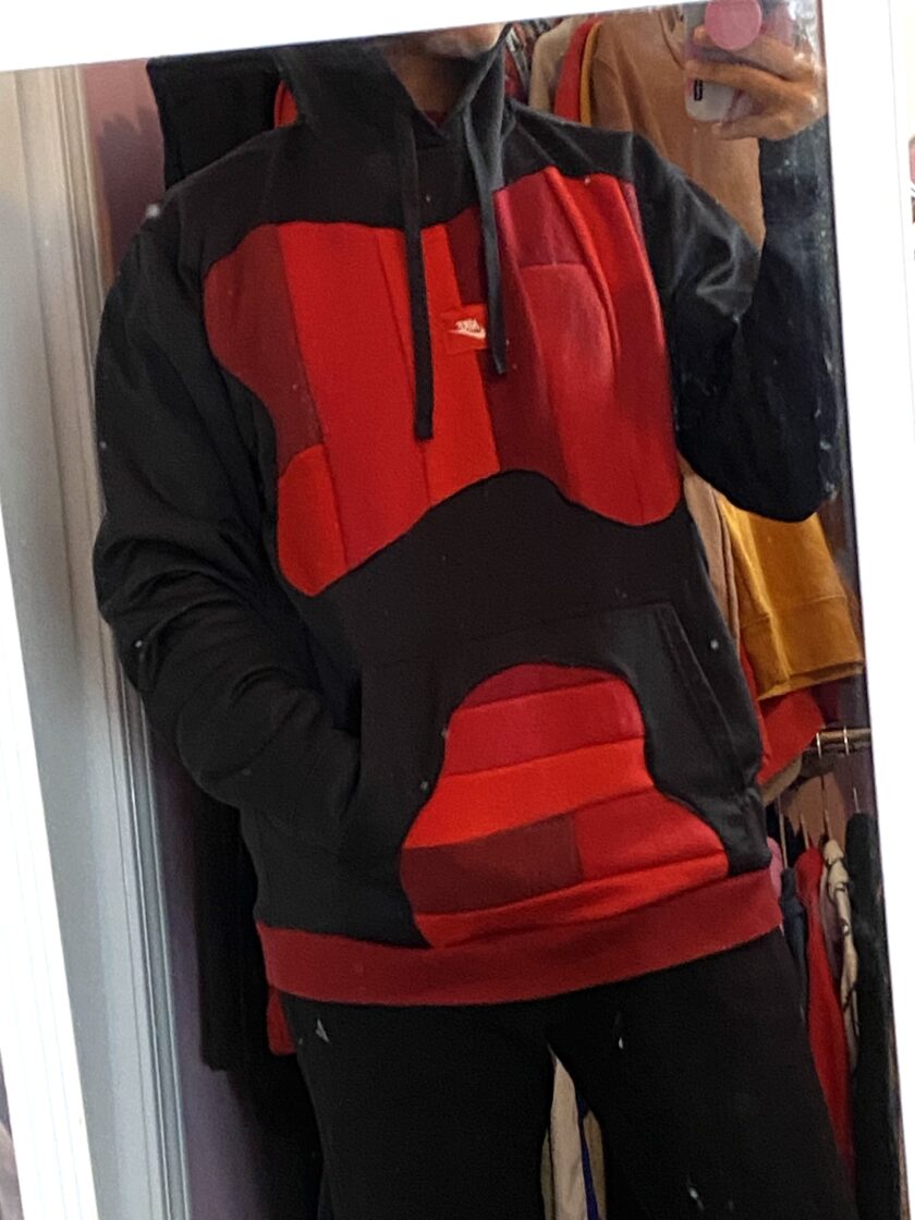 A woman is taking a selfie in a red and black hoodie.