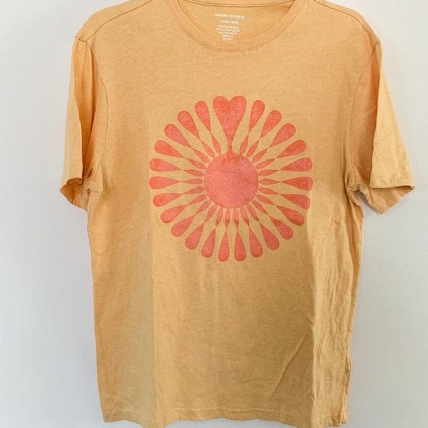 A yellow t - shirt with a sun design on it.