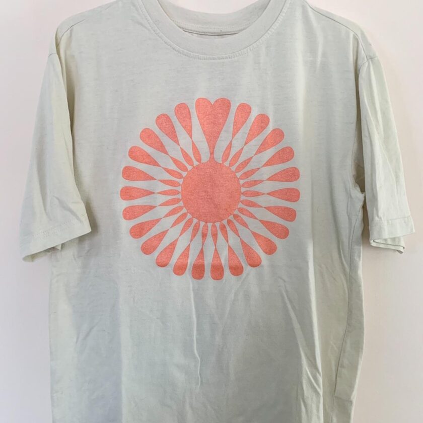 A white t - shirt with an orange flower on it.
