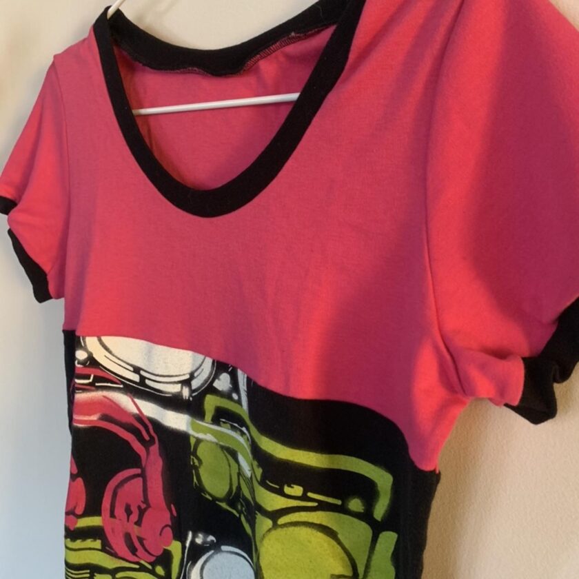 A pink and green t - shirt hanging on a hanger.