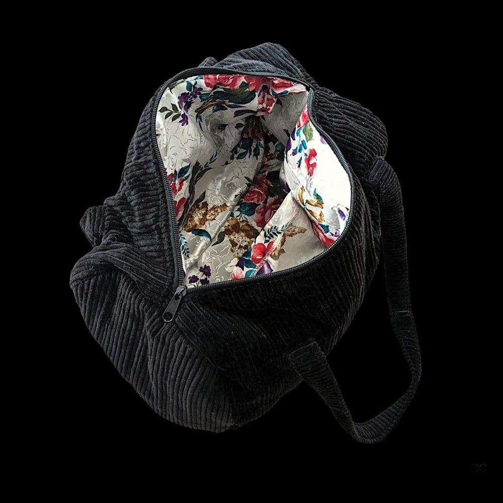 A black duffel bag with a floral pattern on it.
