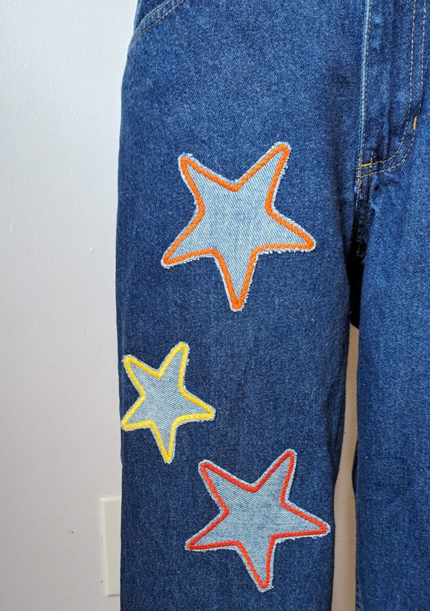 A pair of blue jeans with stars embroidered on them.