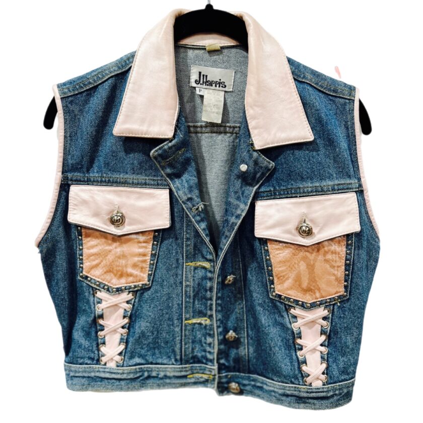 A denim vest with a pink patch on it.