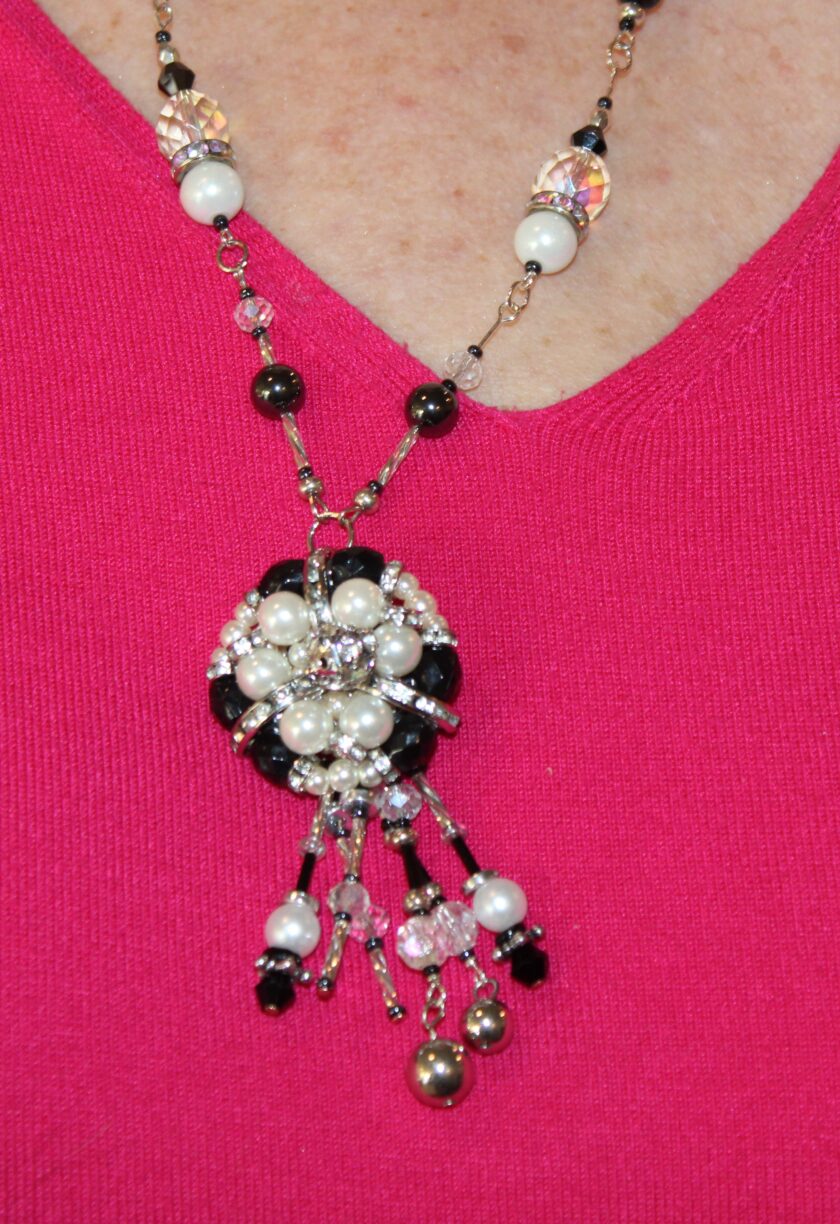 A woman wearing a necklace with black and white beads.