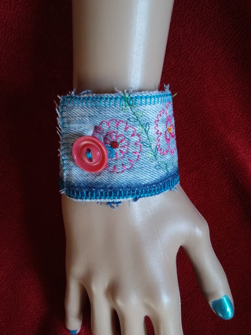 A mannequin wearing a cuff bracelet with embroidered flowers