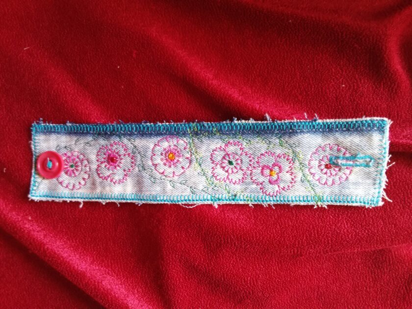 Embroidered flowers adorn a denim cuff bracelet