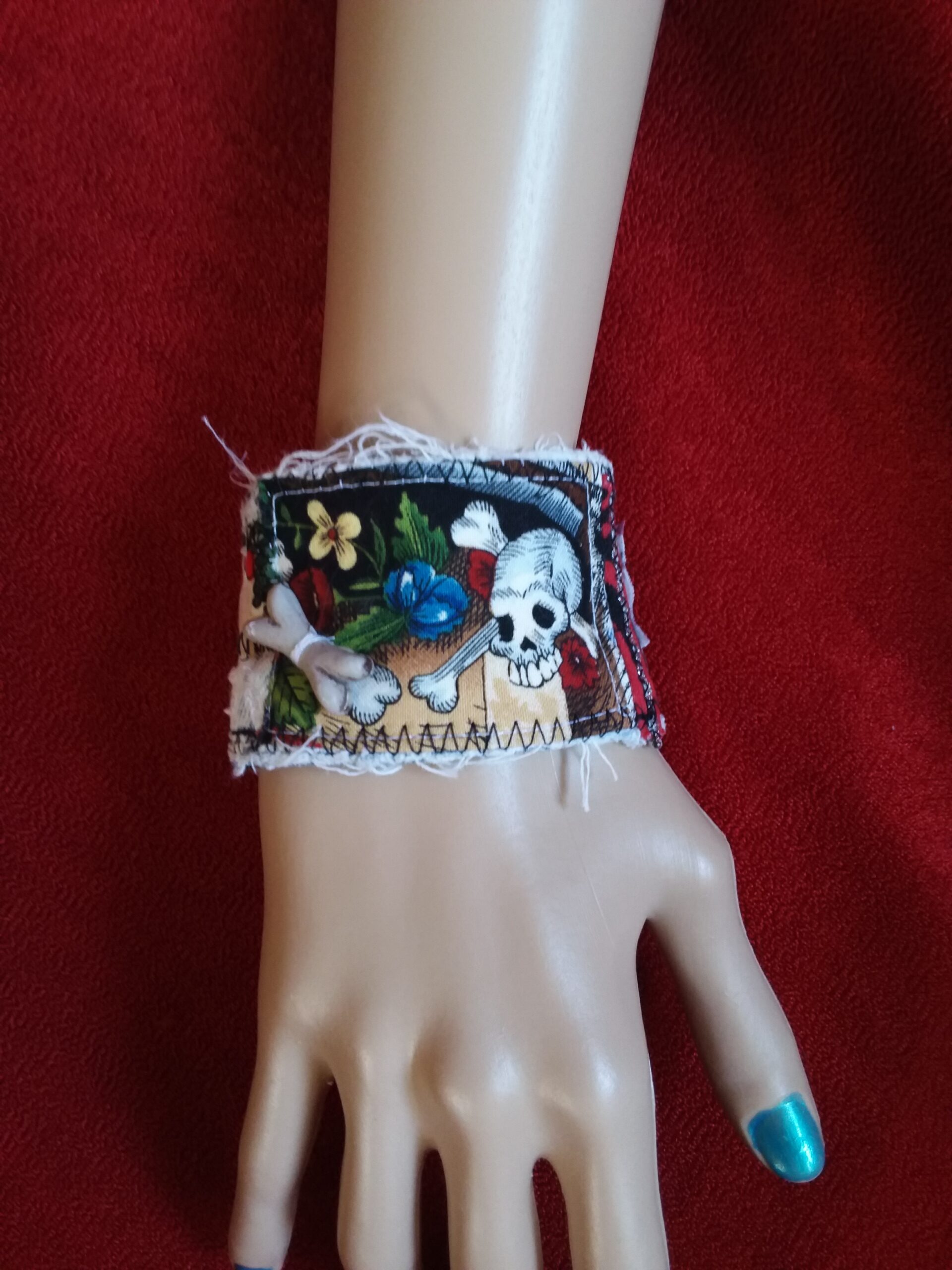 Upcycled denim cuff bracelet with skull and roses on it.