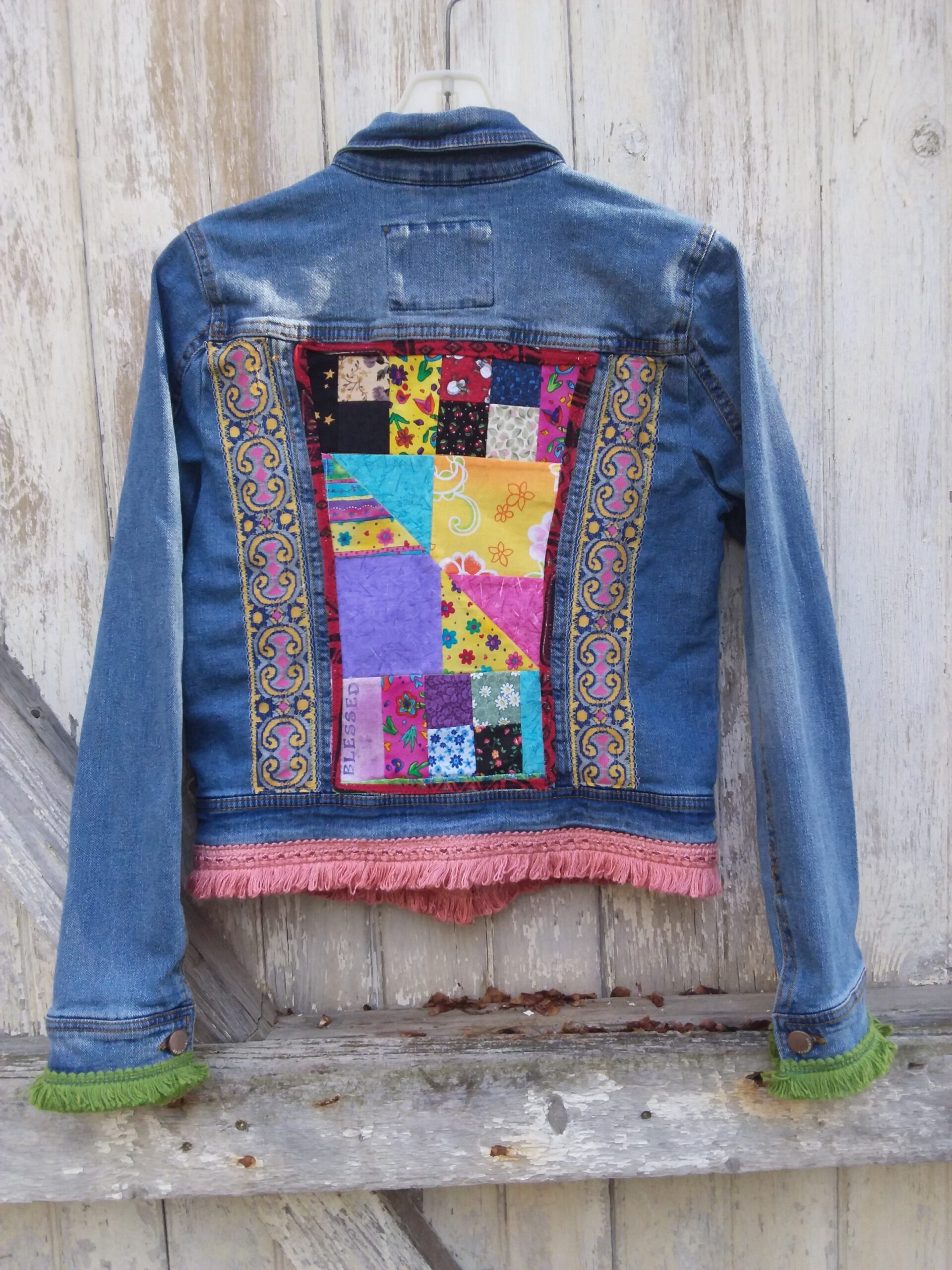 Upcycled denim jacket with bright patchwork panel, lace trim and funky fringe.