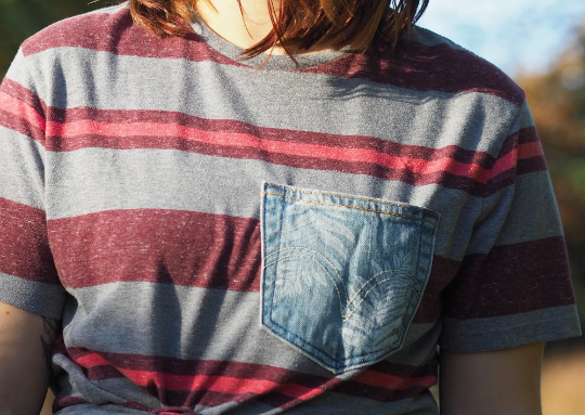 A girl wearing a striped t - shirt with a pocket.