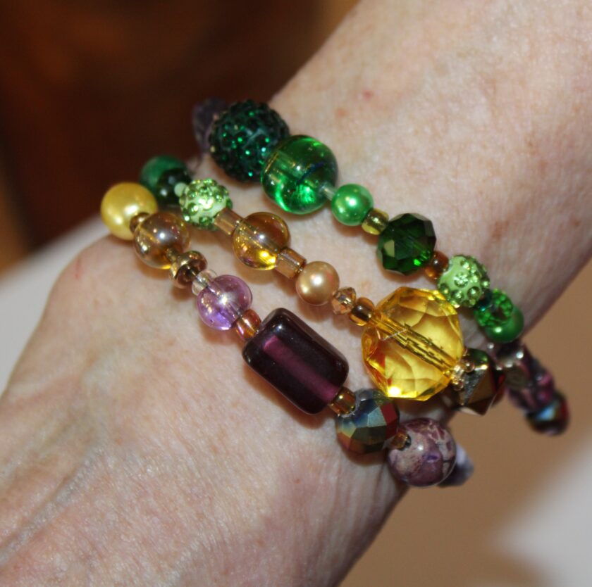 A woman wearing a bracelet with green, yellow, and purple beads.