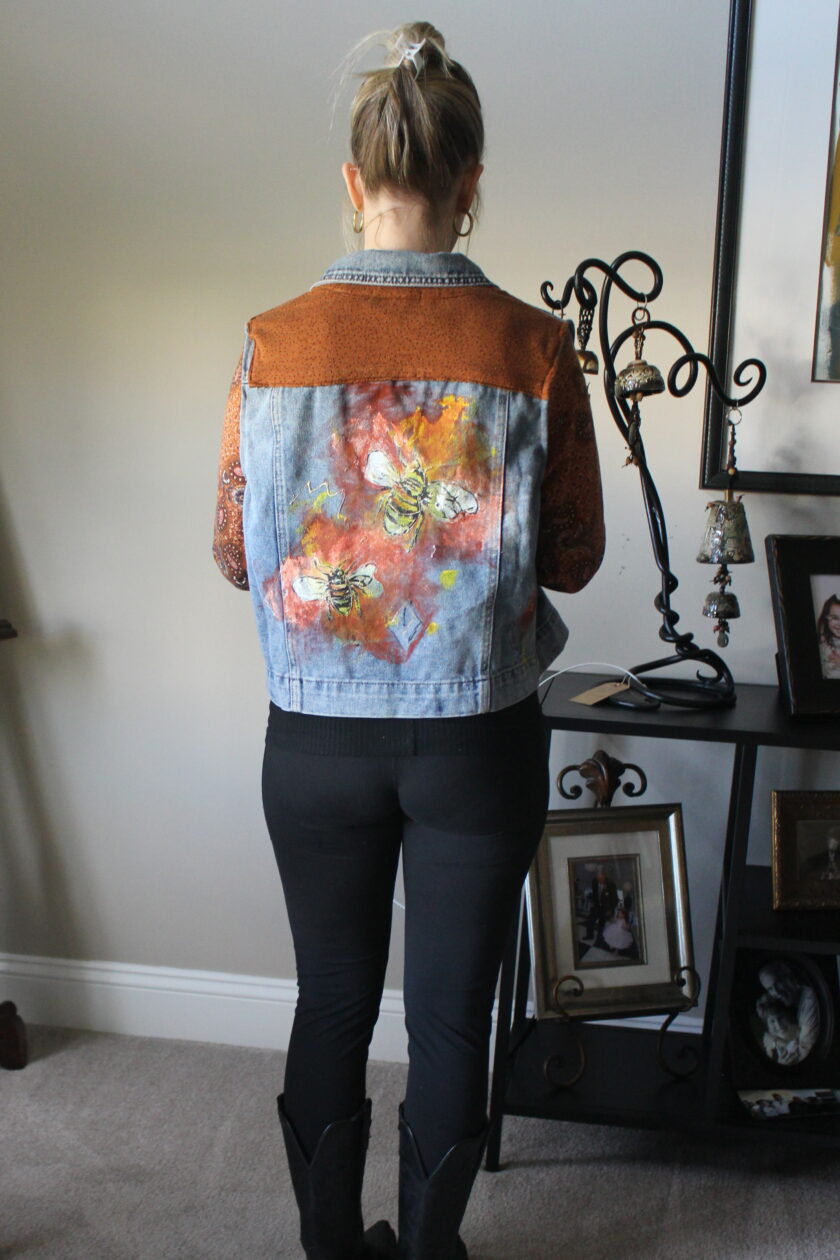 A woman wearing a denim jacket standing in a room.