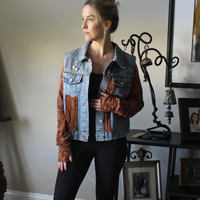 A woman standing in a room wearing a denim jacket.
