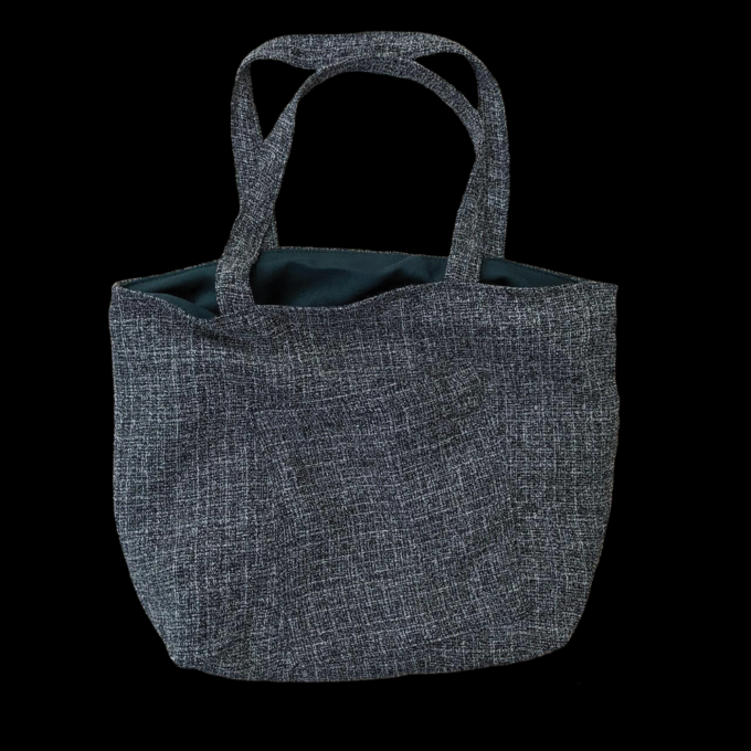 A grey tote bag on a black background.
