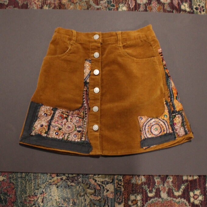 A brown corduroy skirt with embroidered patches.