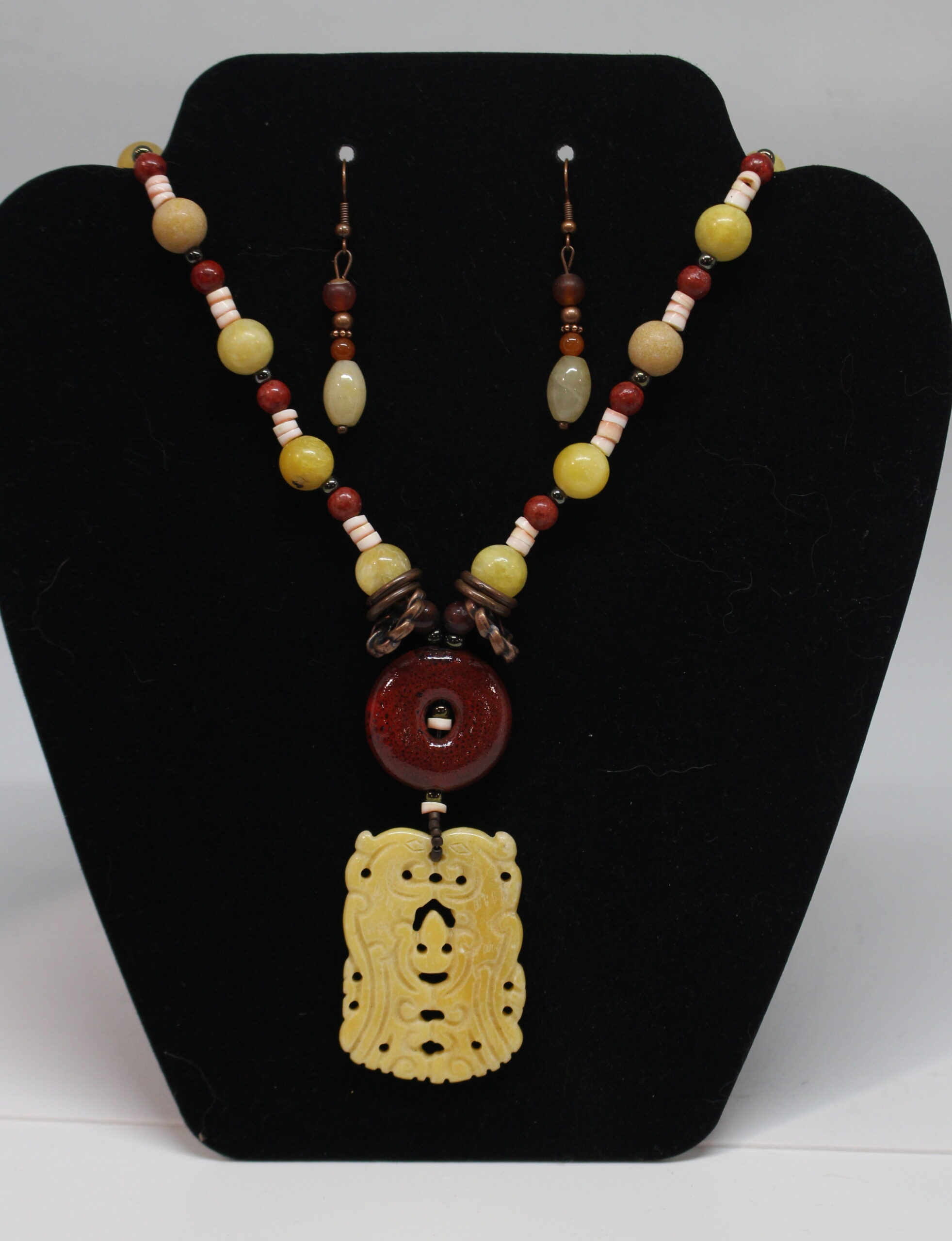 A necklace and earring set with a yellow jade pendant.