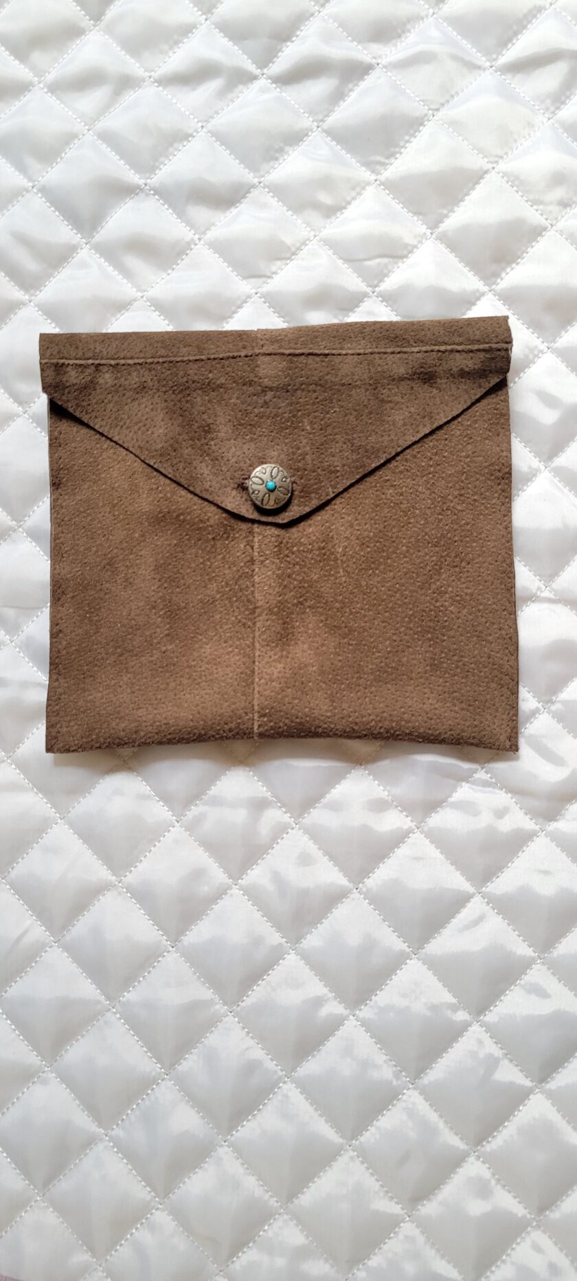 A brown leather bag with a blue stone button.