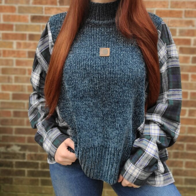 A woman wearing a blue sweater and plaid shirt.