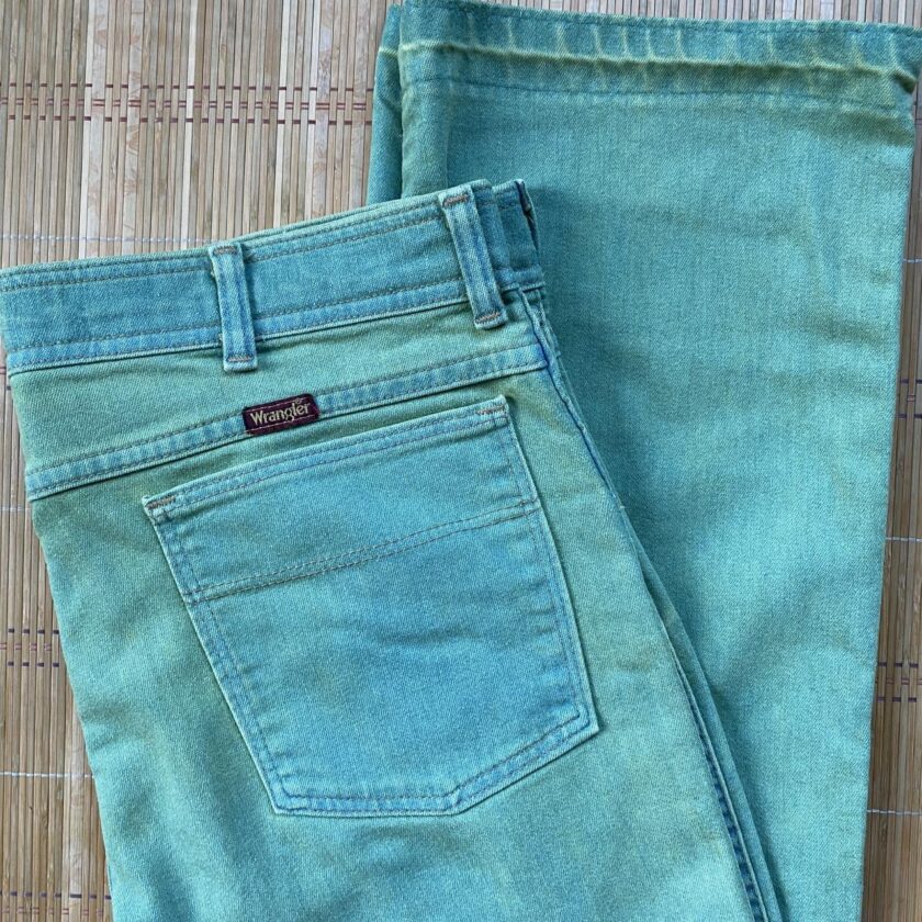 A pair of green jeans on a bamboo mat.