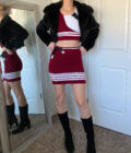 A woman is standing in front of a mirror wearing a red and white cheer skirt.