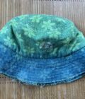 A green and blue bucket hat on a bamboo mat.