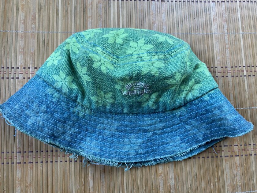 A green and blue bucket hat on a bamboo mat.