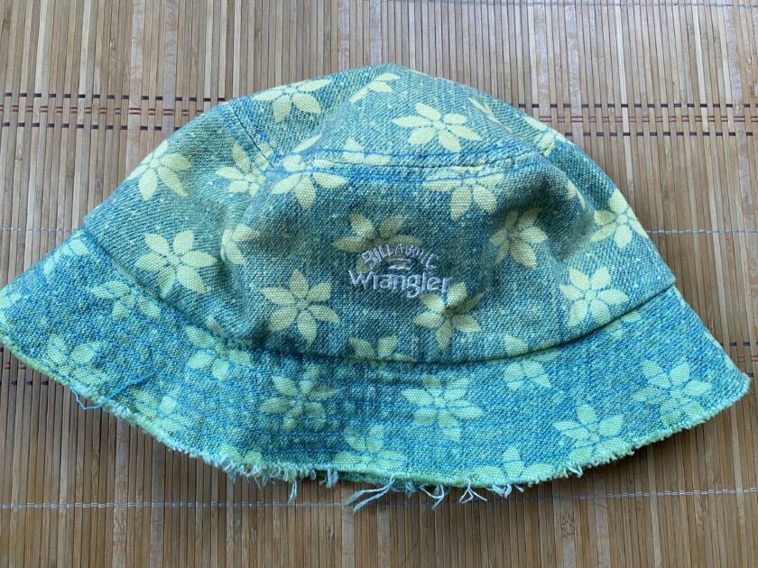 A green and yellow bucket hat on a bamboo mat.