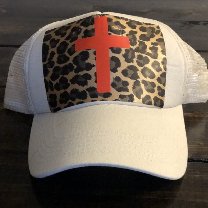 A white hat with a leopard print and a cross on it.