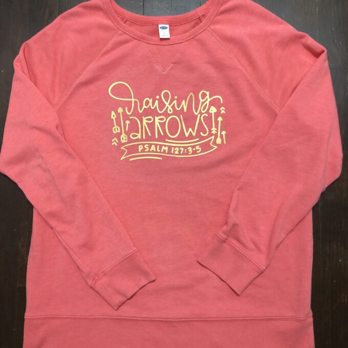 A pink sweatshirt with a gold logo on it.