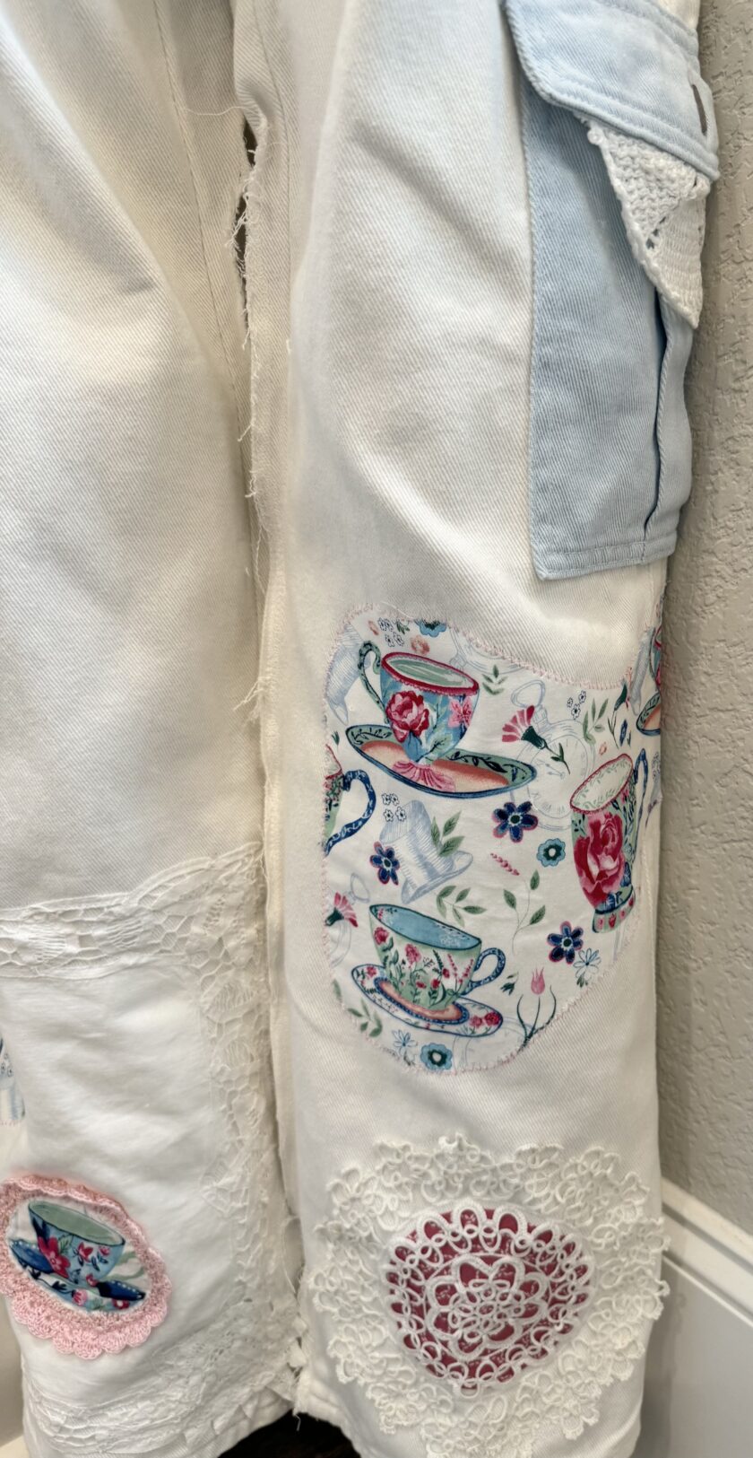 A pair of white pants with embroidered flowers on them.