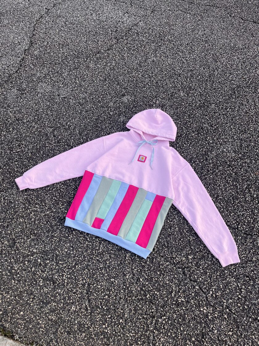 A pink and blue striped hoodie laying on the ground.
