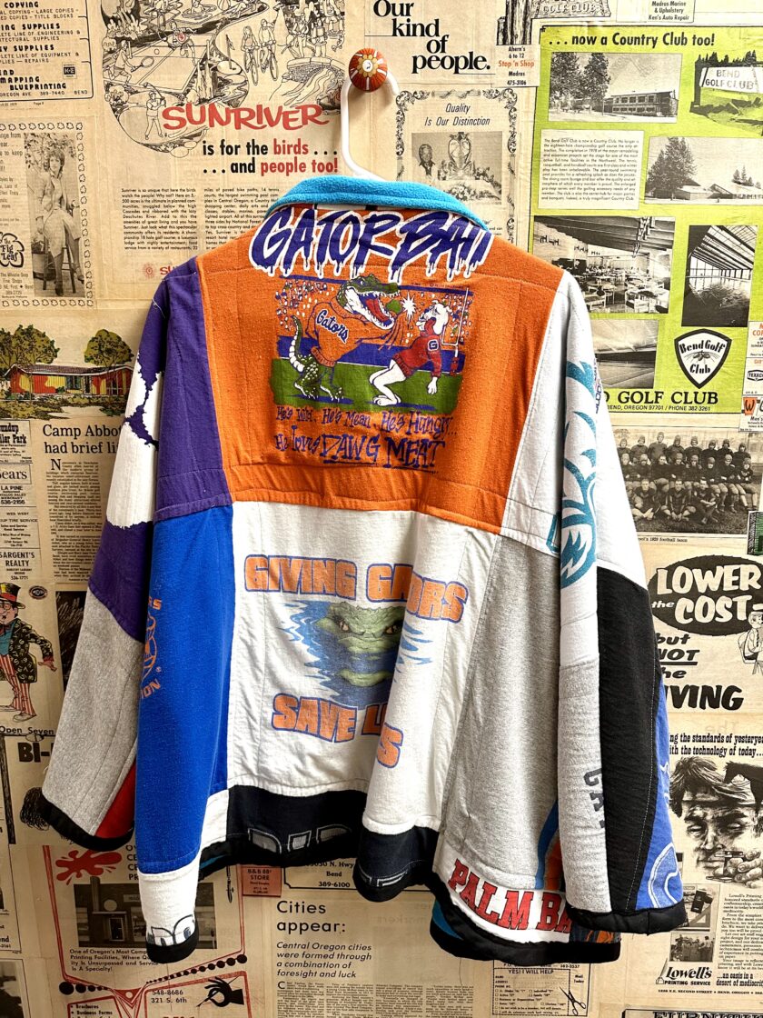 A jacket hanging on a wall with many different designs on it.