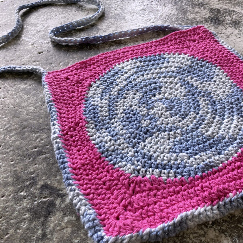 A crocheted bag with a pink and gray design.