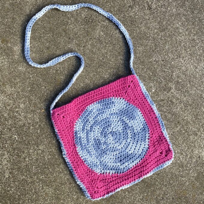 A crocheted bag with a blue and pink design.