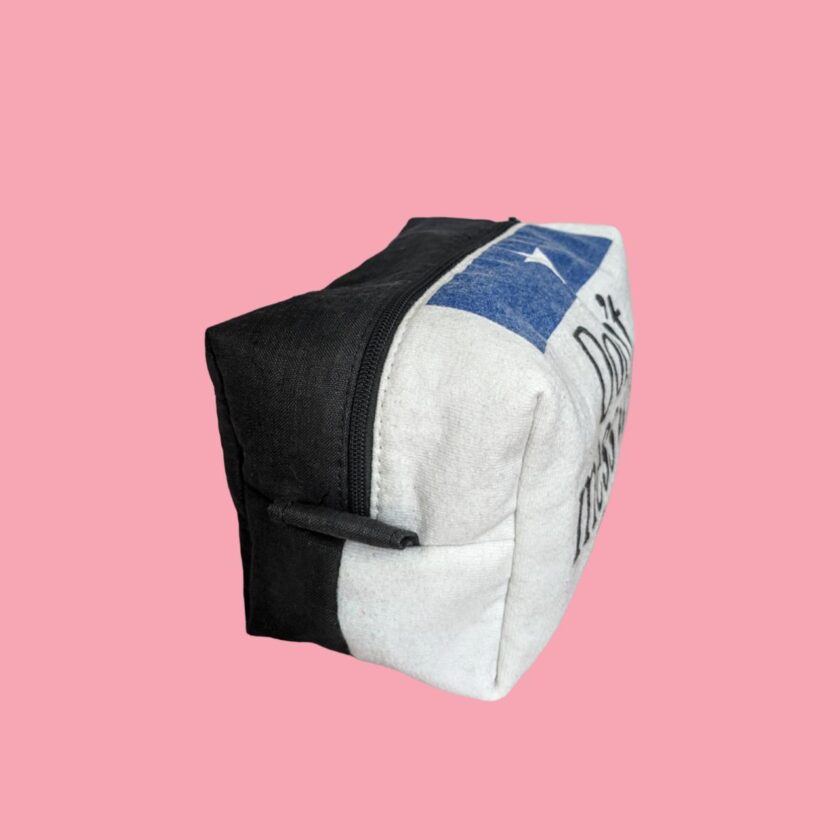 A white and black toiletry bag on a pink background.