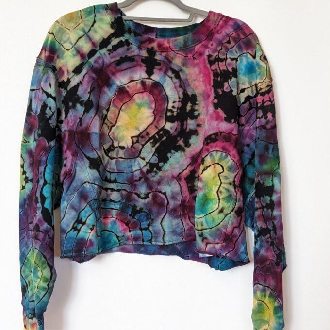 A tie dyed sweatshirt hanging on a hanger.