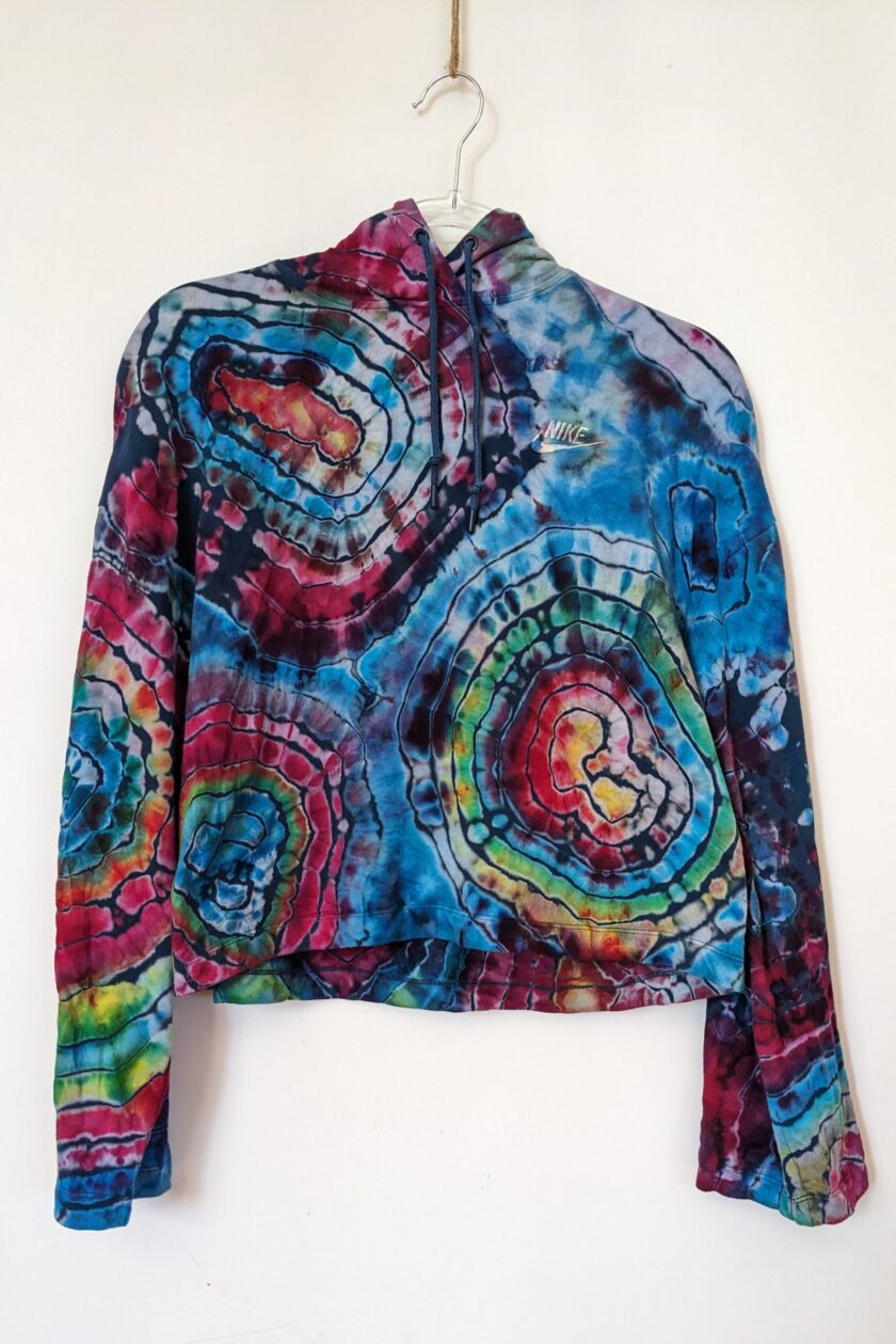 A tie dyed jacket hanging on a wall.