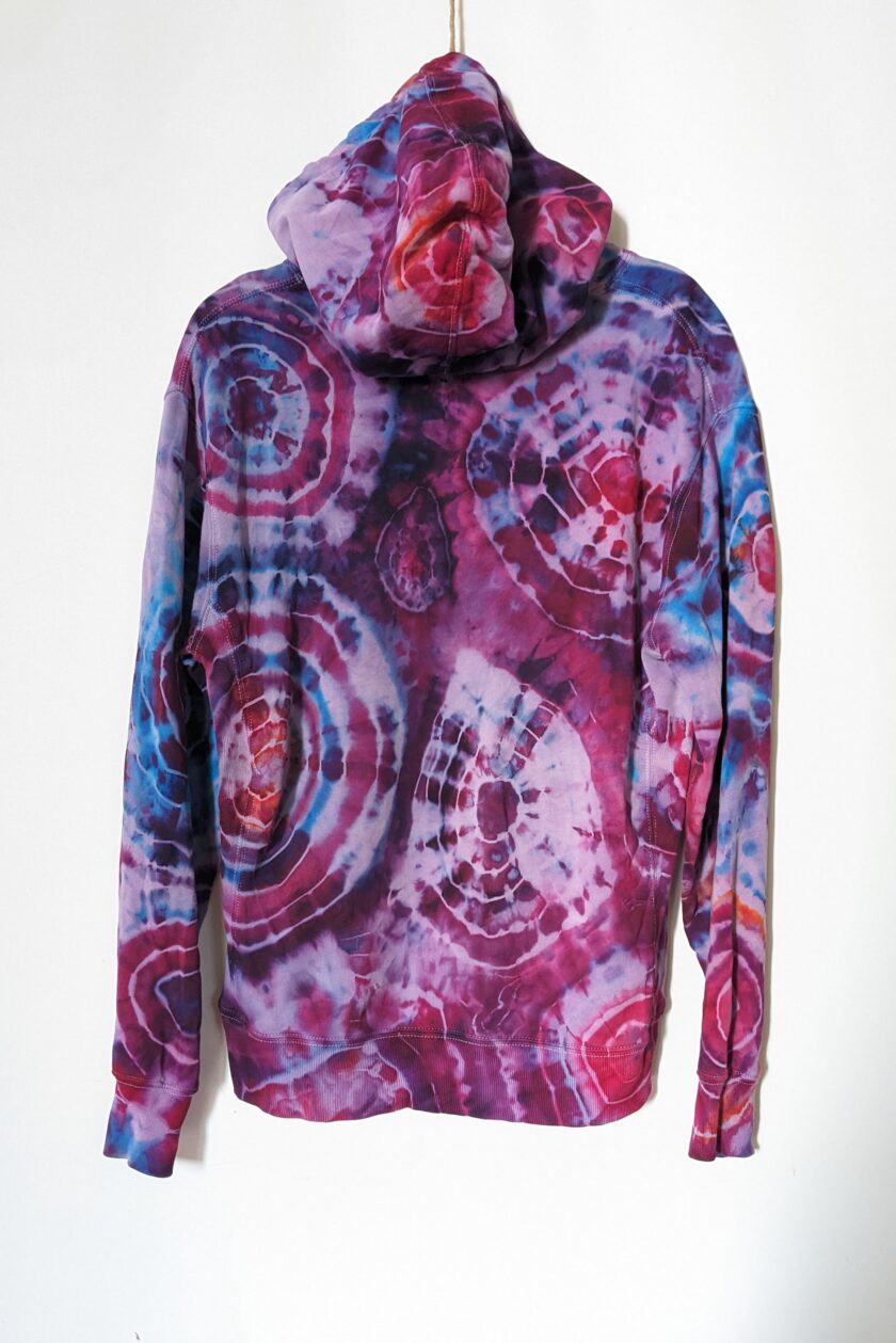 A tie dyed hoodie hanging on a hanger.